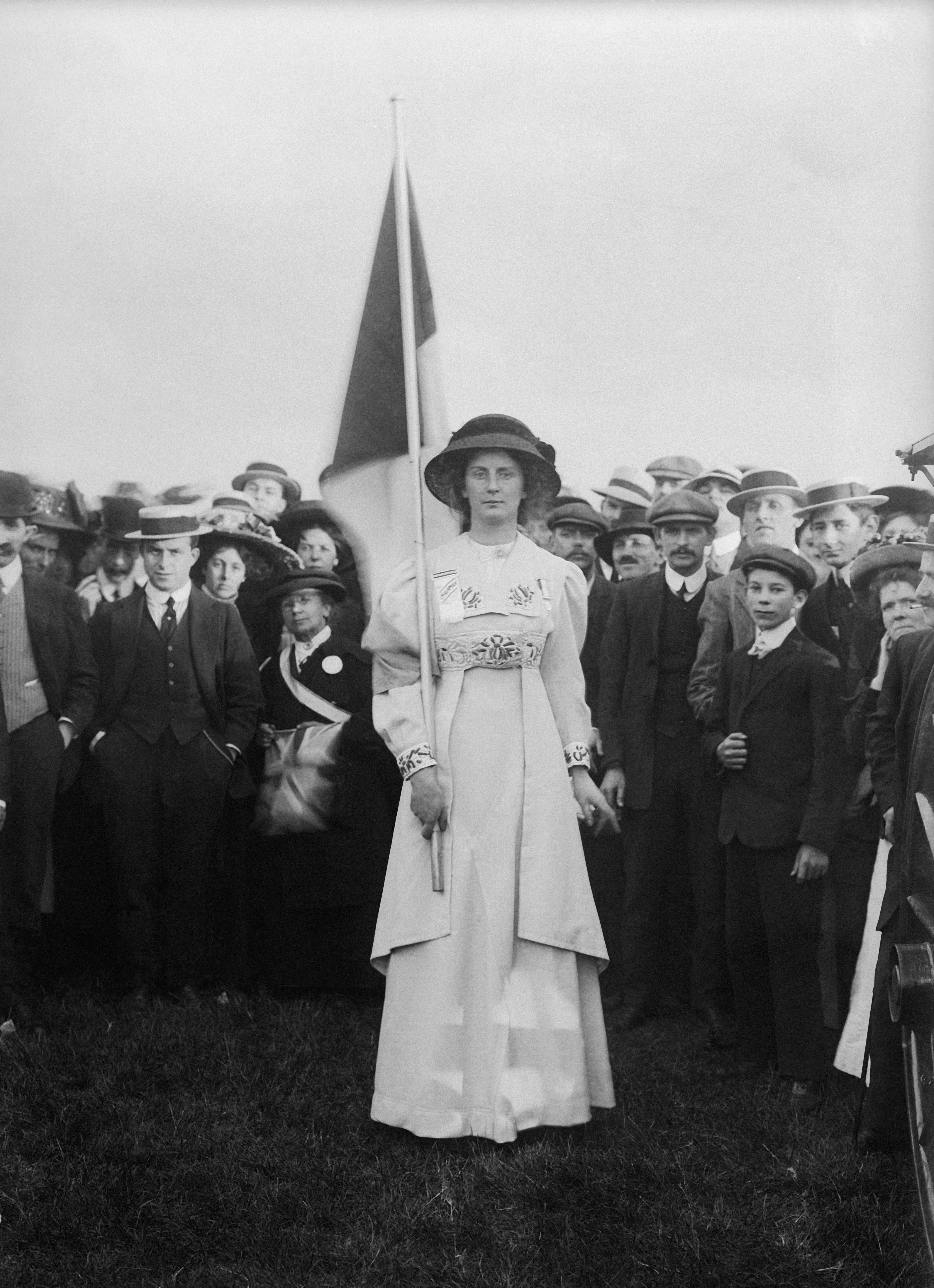 Suffragette Charlotte Marsh in Hyde Park wearing a prisoner's medal and carrying the purple, white and green tricolour flag.