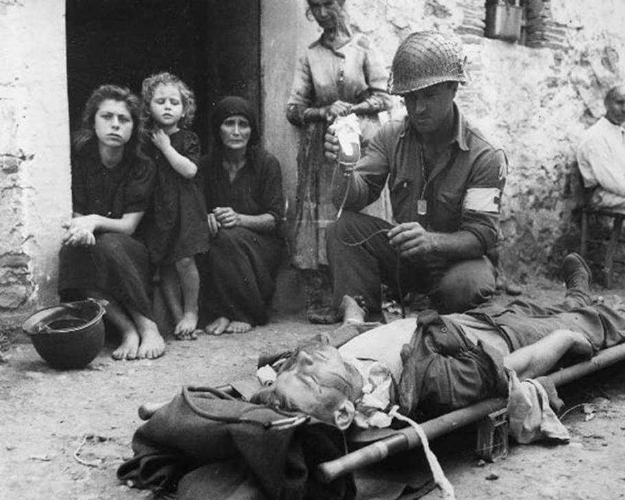    Un soldato americano soccorre un suo compagno colpito dalle schegge di una bomba, 8 agosto 1943, Sicilia  Autore sconosciuto o non fornito © U.S. National Archives and Records Administration
